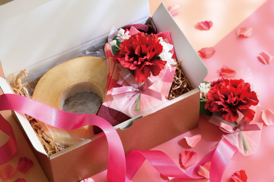ピンクのボックスの中にバウムクーヘンとカーネーションの造花ブーケが入ったギフト