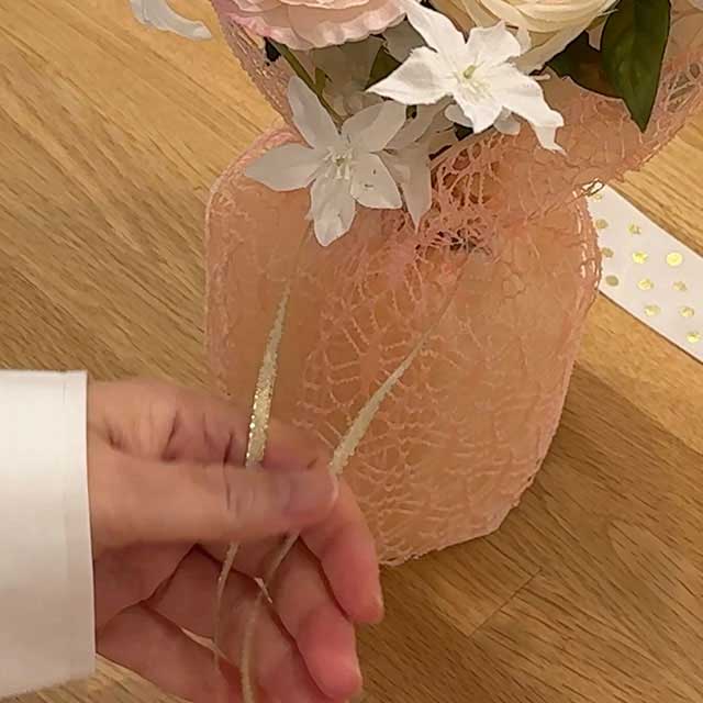 ［3］細いリボンでブーケバッグのステム部分をひと結びします｡
